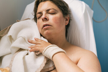 Woman trying to sleep with a blanket in hospital room.