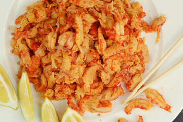 boiled craw fish meat on the plate with lemon slices, Japanese sticks, salad and straw mat closeup photo