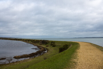 Footpath along The Solent Way trail at Lymington Hampshire England on a winter day with cloudy sky background