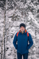 Fototapeta na wymiar Man in winter jacket walking in snowy winter forest, snowy winter day