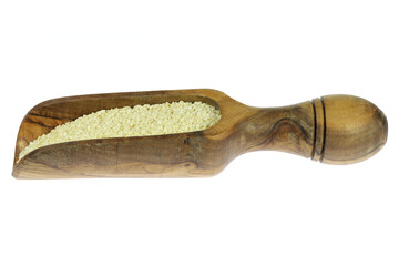 sesame seeds in an olive wood weighing scoop isolated on white background