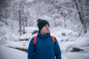 Man in winter jacket walking in snowy winter forest, snowy winter day
