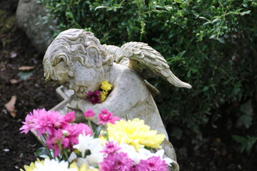 Friedhofsengel mit Blumen auf einem Grab auf dem Friedhof in Sommer