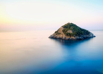 the island of bergeggi in the middle of the silk effect sea on a quiet summer morning in western...