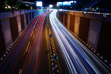 Fototapeta na wymiar Photo of light trails of vehicle traffic in the dark of night from above the height of the flyover in the city of Denpasar, Bali, Indonesia