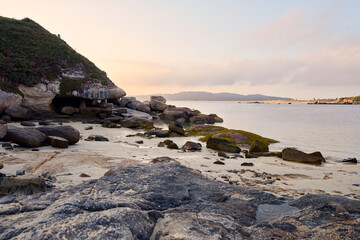 Galician beach with rocks and blue sky. Nature background.