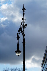 Fototapeta na wymiar City lantern lit by the sun on the grey clouds background