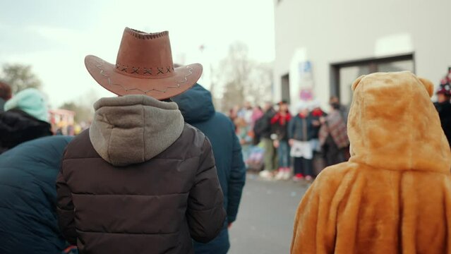 Kind mit Cowboy Hut steht neben einem verkleideten Kind am Rosenmontagszug während Karneval