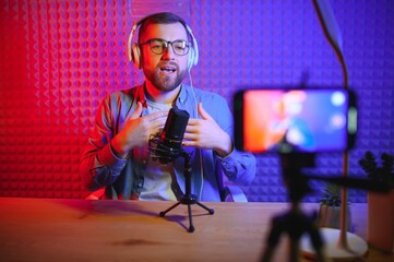 A video blogger records content in his studio. The host of the video blog is a young man who is very enthusiastic about telling his subscribers a story.