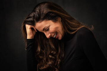 Headshot of a happy woman in profile against isolated dark background