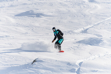 Fototapeta na wymiar Freerider on snowboard masterfully ride down off-piste in deep fresh snow in Gudauri Georgia