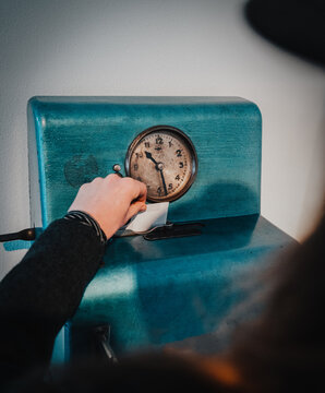 Femal hand is putting card into old fashioned time clock