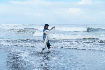 Fisherman holding his net entering the sea.