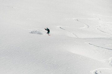 awesome beautiful view of a snow-covered mountain slope and a man on a snowboard speedly slides...