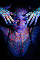 Fashion model woman in neon light, portrait of a beautiful model with fluorescent makeup, artistic design of disco dancers posing in UV, colorful makeup. Isolated on black background.