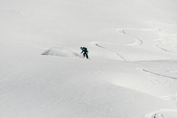 amazing view of a snow-covered mountain slope and a man on a snowboard speedly slides down....