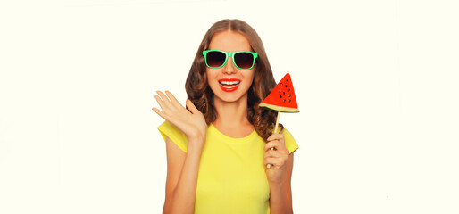 Fototapeta na wymiar Summer portrait of happy smiling young woman with lollipop or ice cream shaped slice of watermelon wearing sunglasses on white background