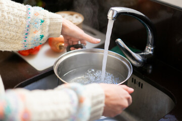 Girl cooking. Girl putting water in the pot