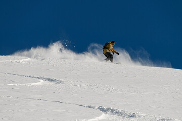 great view snow-covered mountain slope along which a freerider rides down against the blue sky