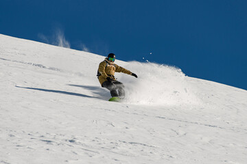 male snowboarder skilfully descends down a snowy mountain slope