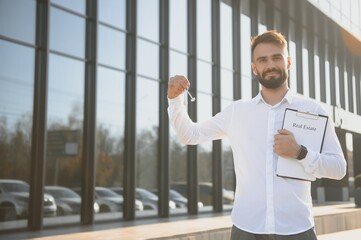 Male Realtor Standing Outside Residential Property Holding Keys