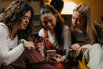 Front view of a three woman using a phone and a credit card to shop online