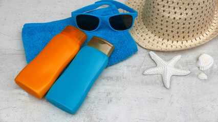 Sonnenschutzprodukte auf einem Handtuch mit Sonnenbrille und Hut.	