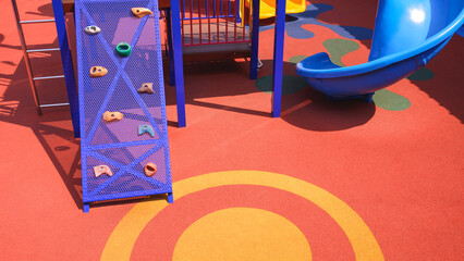 Jungle gym and slider with playground equipments on colorful rubber floor in outdoors playground area