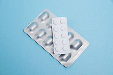 Pills in blisters on a blue paper background. Probiotics and antibiotics in the package.