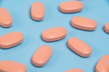 Obraz na płótnie Canvas Pattern, pink capsules with vitamins on a blue paper background, flatlay