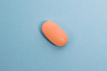 Pink pill macro on blue paper background with copy space