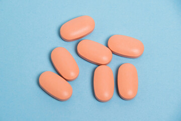 Many pink flatlay pills on a blue paper background. Concept of treatment and maintenance of immunity with vitamins