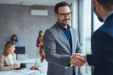 Portrait of cheerful young manager handshake with new employee. Business partnership meeting in...