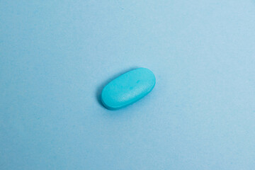 Vitamins in pills on blue paper background, medical capsule close-up