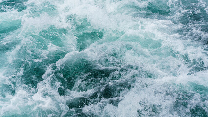 Fototapeta na wymiar White splash foams behind a ship engine on the sea. Foam bubbles on sea water surface .