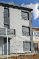 Balkone mit Metall-Geländer und Kunststoff-Plattenverkleidung sowie französische Balkone an moderner Neubau-Hausfront mit Wellblechprofil-Fassadenverkleidung