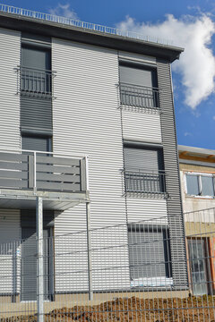 Balkone mit Metall-Geländer und Kunststoff-Plattenverkleidung sowie französische Balkone an moderner Neubau-Hausfront mit Wellblechprofil-Fassadenverkleidung