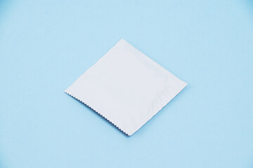 Condom in white packaging on a soft blue background
