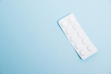 White blister pack with antibiotic pills on blue paper background, top view