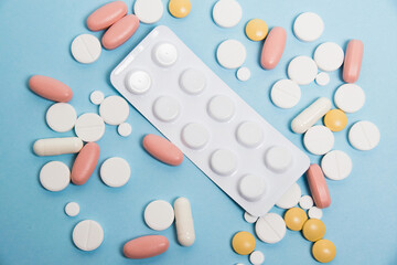 Blister with antibiotics and colorful flatlay pills on blue paper background