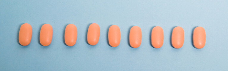 Medical background, flatlay, banner, many pink pills on blue paper background