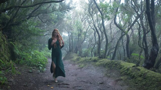 Beautiful woman in an elf costume is walking in a magic green enchanted forest.
