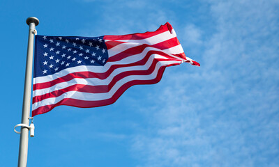 Flag of United States waving in the wind at sunny bright day.