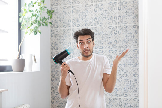 Funny Man Amusing With Hair Dryer In The Bathroom During Daily Morning Routine. Bad Hair Day Concept