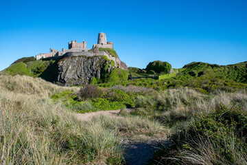 Fototapeta na wymiar Bamburgh Castle from across the sandy dunes on the beach. Northumberland, UK