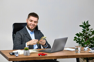 young bearded businessman working on laptop and holding money