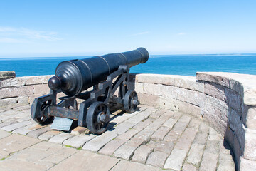 Cannon pointing out towards sea at Bamburgh Castle in Northumberland, UK