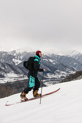 side view of male skier walking against winter mountain landscape