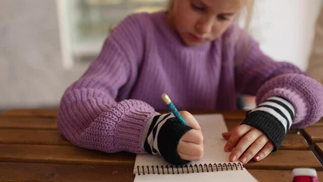 Focus on young girl's hands drawinf with a pencil in a sketch book