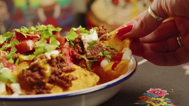 Eating Traditional Mexican food, tex mex cuisine nachos served with meat and vegetables, Taking cooked quesadilla from wooden tray, hot chilli salsa with guacamole top view.